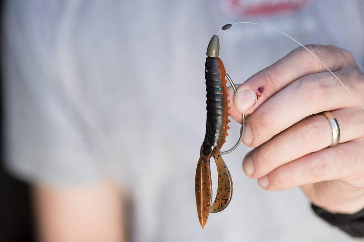 Green pumpkin soft plastic lure on hook, held by fingers