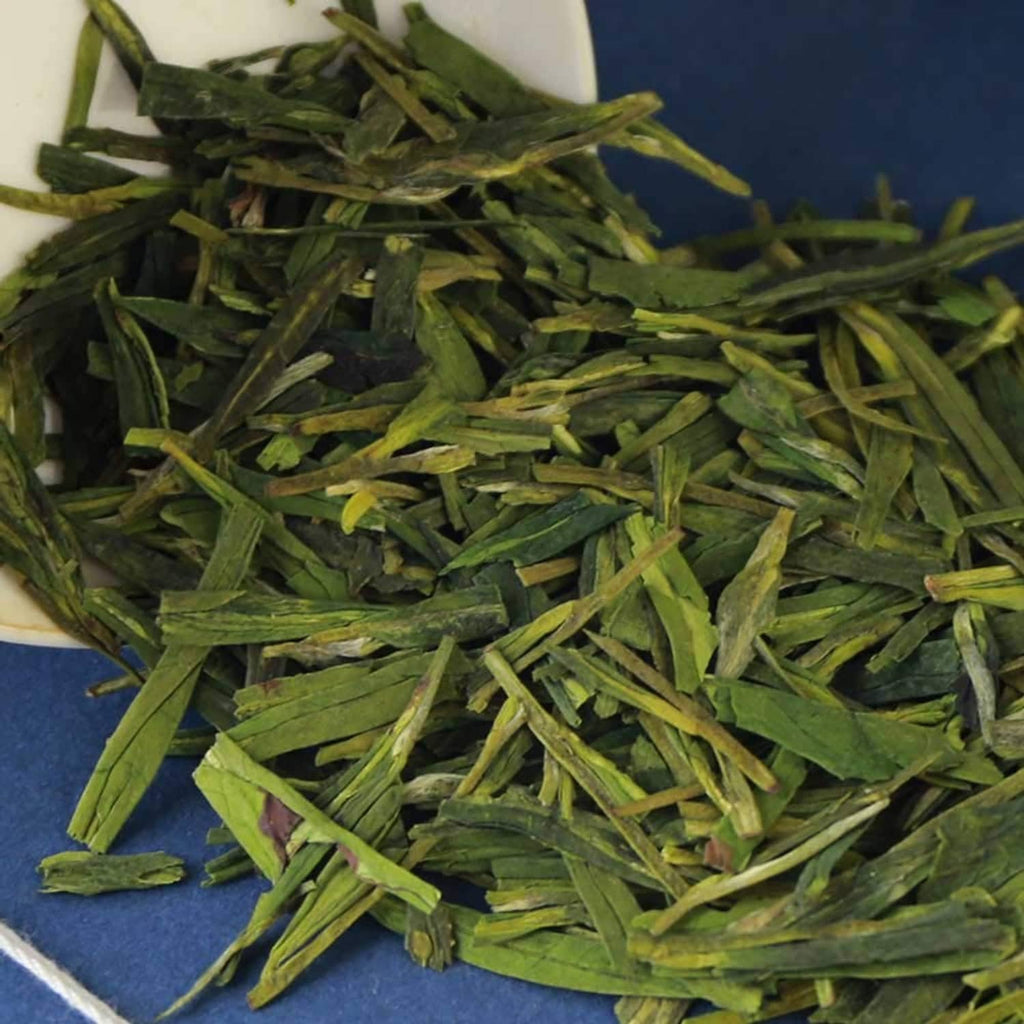 Close-up of loose green tea leaves with slender, curled blades