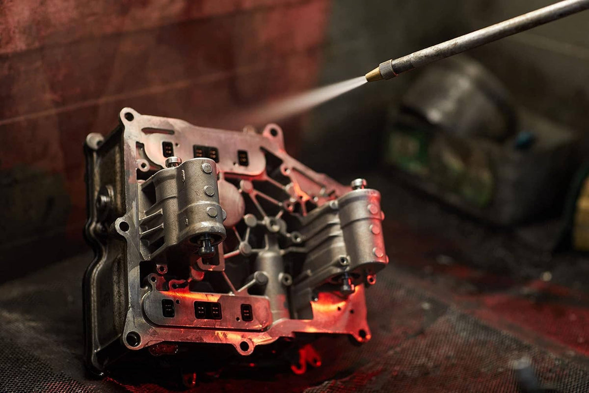 Metal engine components on a work surface being blast-finished by hand