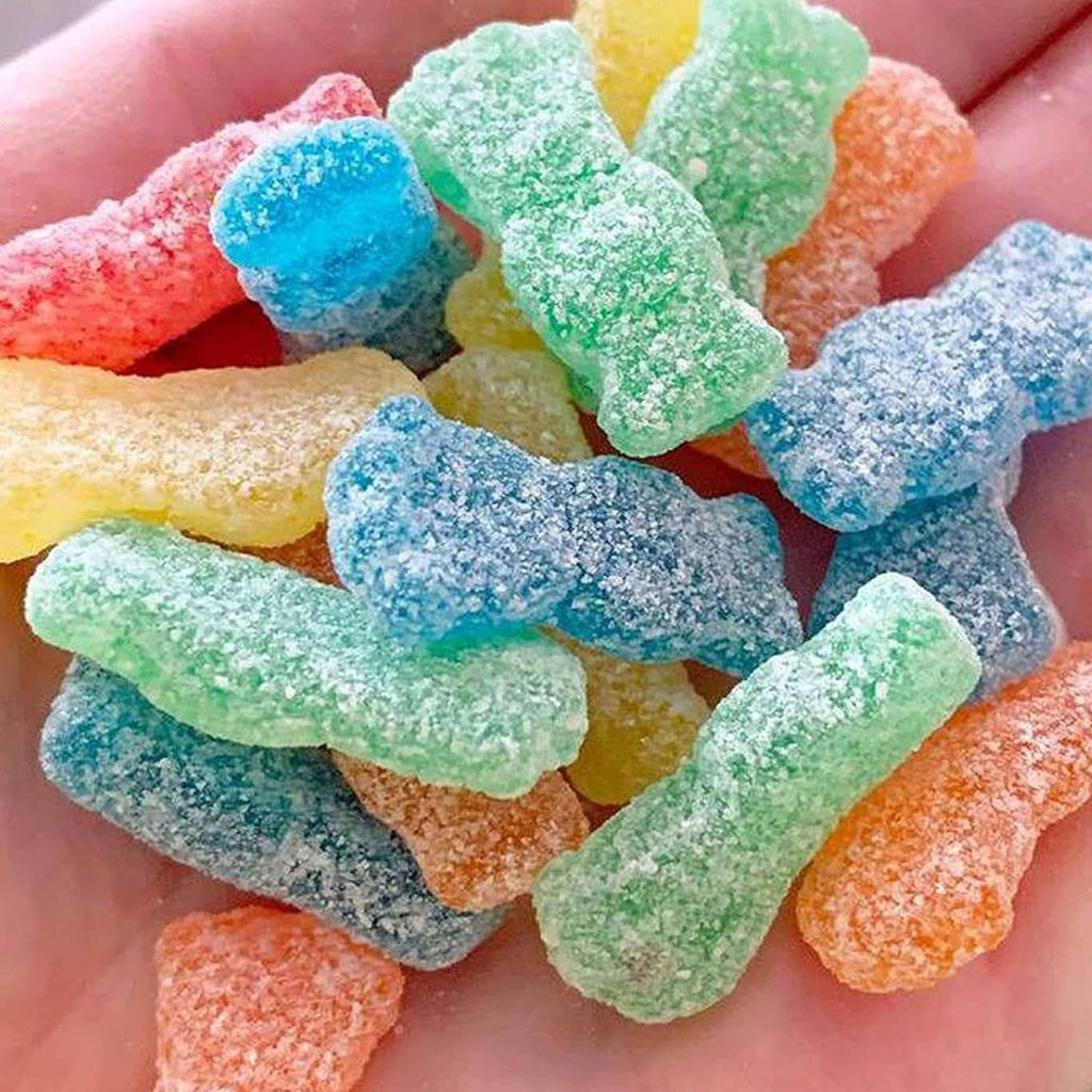 Assorted sour gummy candy pieces in hand, blue, green, yellow, orange and pink