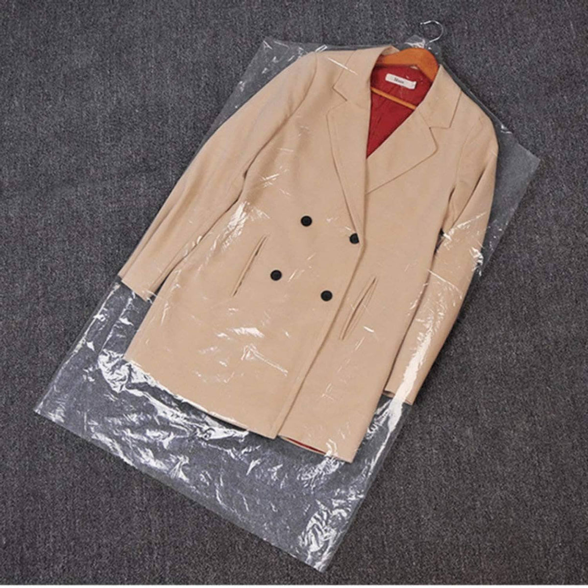 Transparent garment cover bag holding a beige double-breasted coat