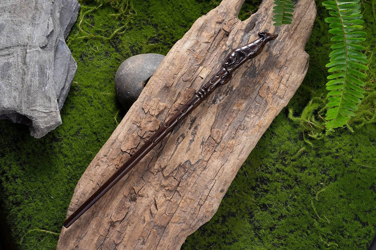 Dark brown carved wooden wand with pointed end and ornate handle