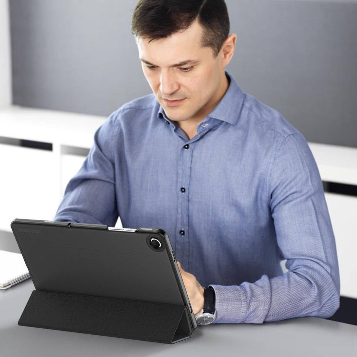 Black tablet case with kickstand propping tablet while in use on a desk