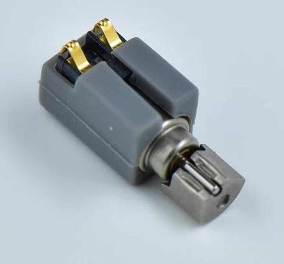 Single grey vibration motor with metal shaft and gold terminal contacts, close-up