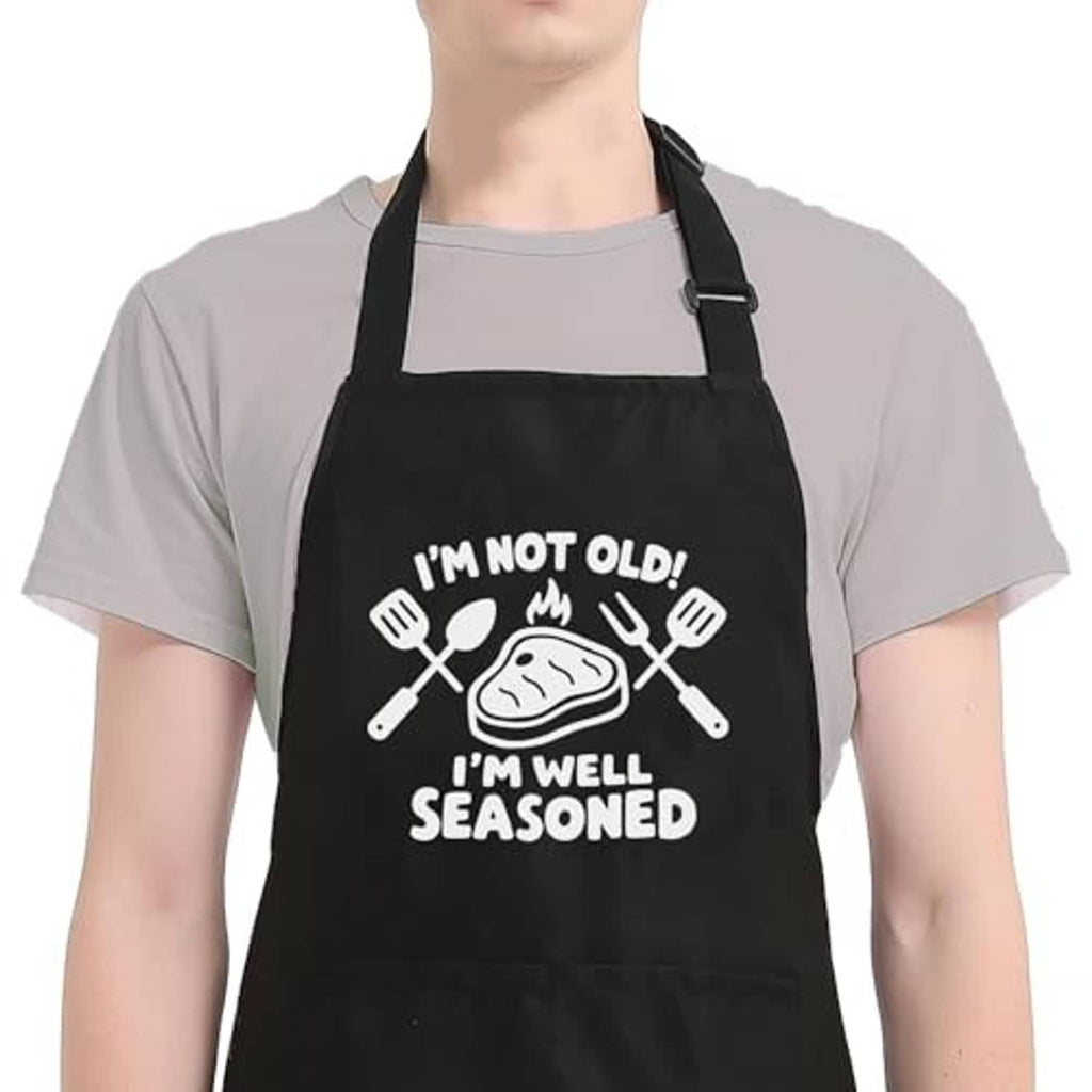 Black kitchen apron with wide neck strap and "I'm well seasoned" cooking graphic