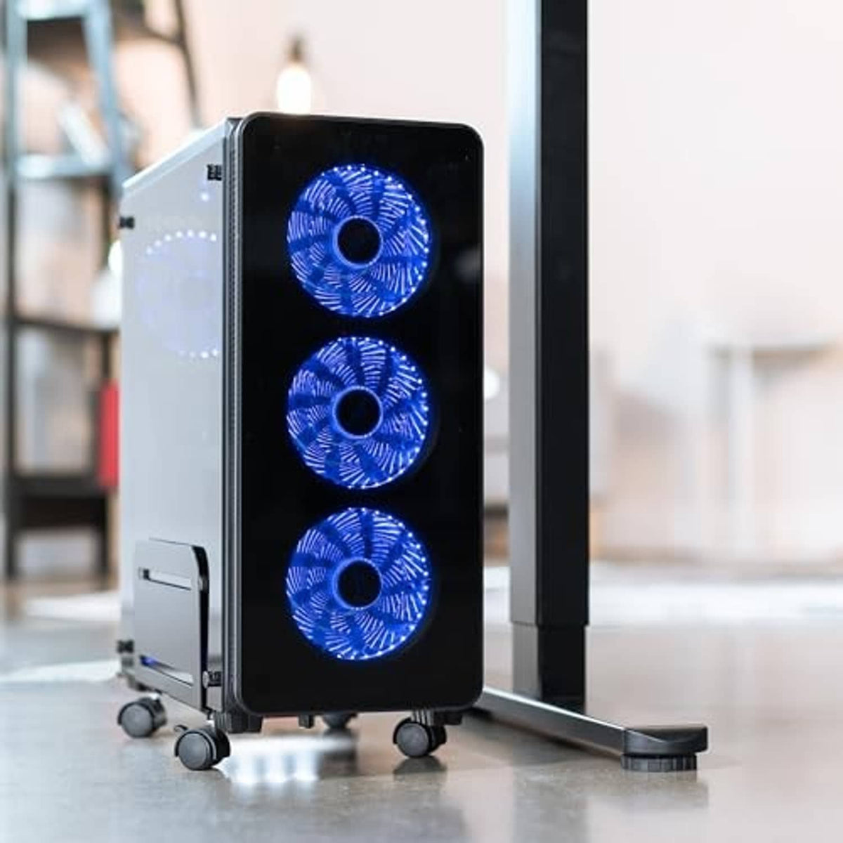 Black mid-tower PC case on rolling stand with three blue-lit fans and casters