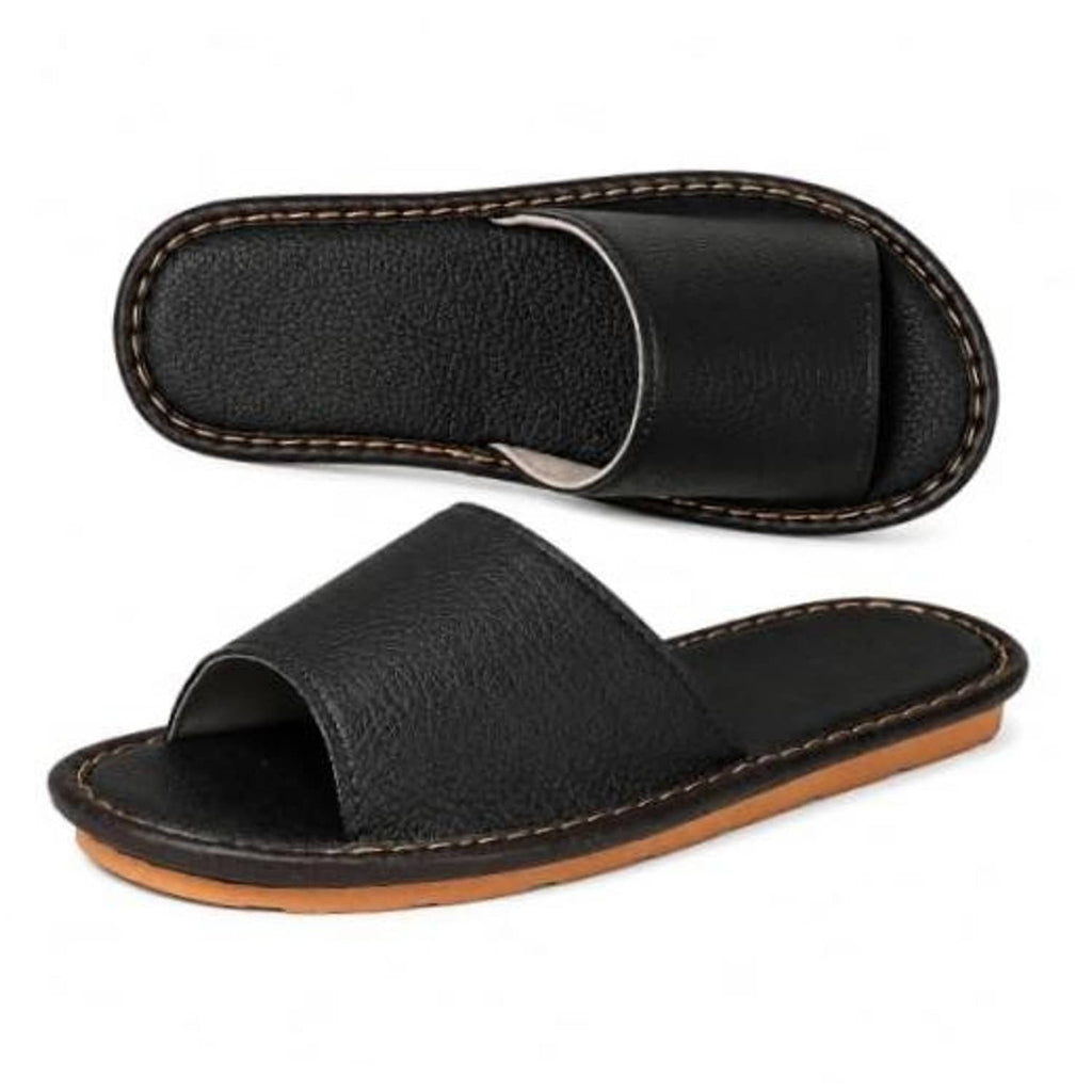 Black open-toe slide flat sandal slipper with tan stitched edge and textured sole.