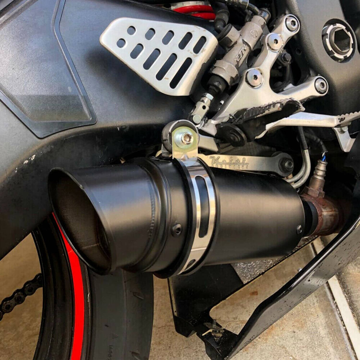 Black slip-on exhaust muffler installed on a motorcycle near the rear wheel.