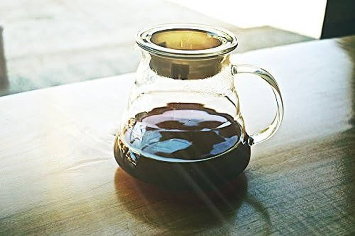 Clear glass coffee carafe with dark coffee inside and side handle