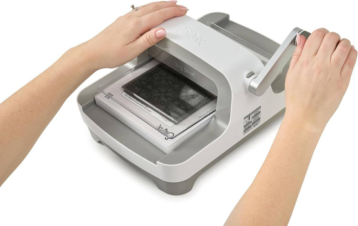 Sizzix Big Shot die-cutting machine with hands placing material in the tray