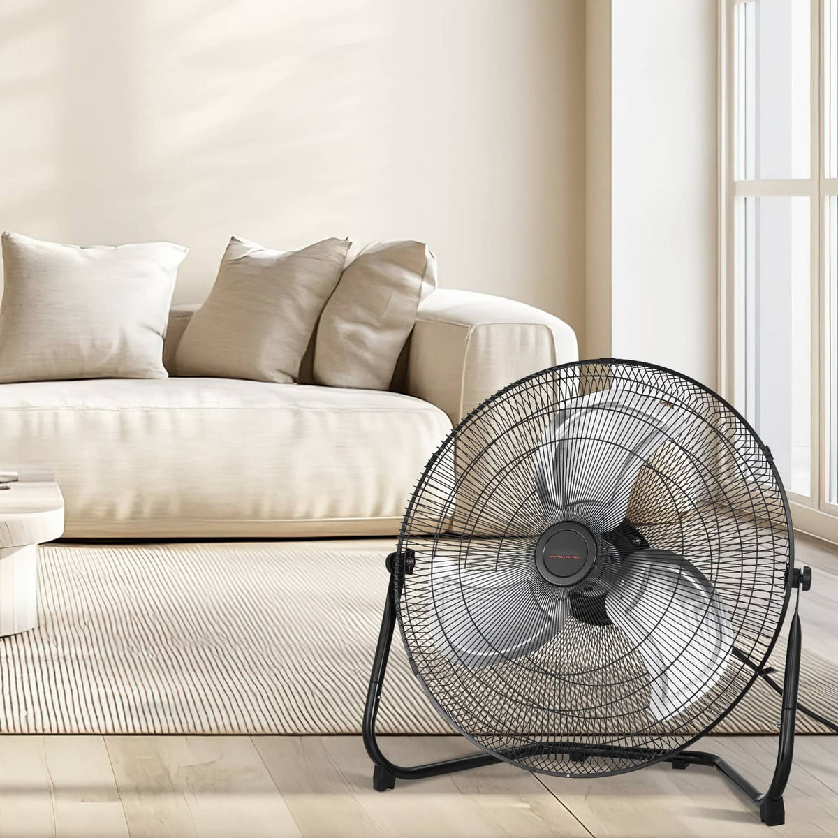 Black metal floor fan with wire grille and adjustable base near a couch