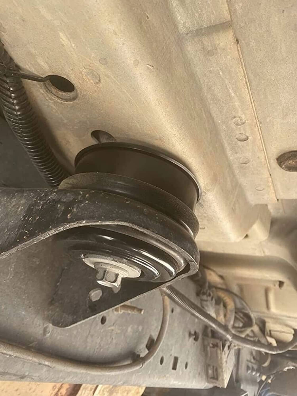 Body mount bushing with black collar and red ring between metal brackets