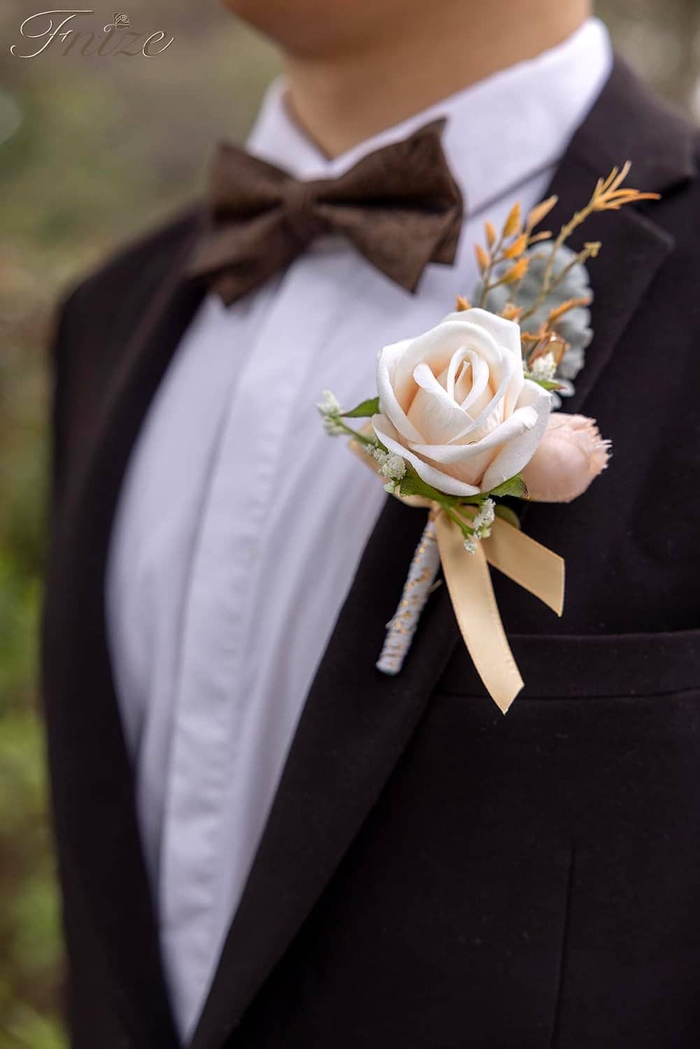Boutonniere on a black suit lapel: cream rose with greenery and champagne ribbon
