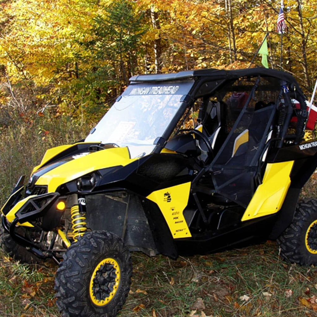 UTV full windshield with clear panel and black side clamps, mounted on a yellow vehicle