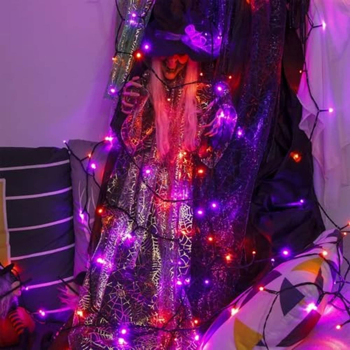 Green-wire LED string lights glowing purple with orange accents on Halloween decor.