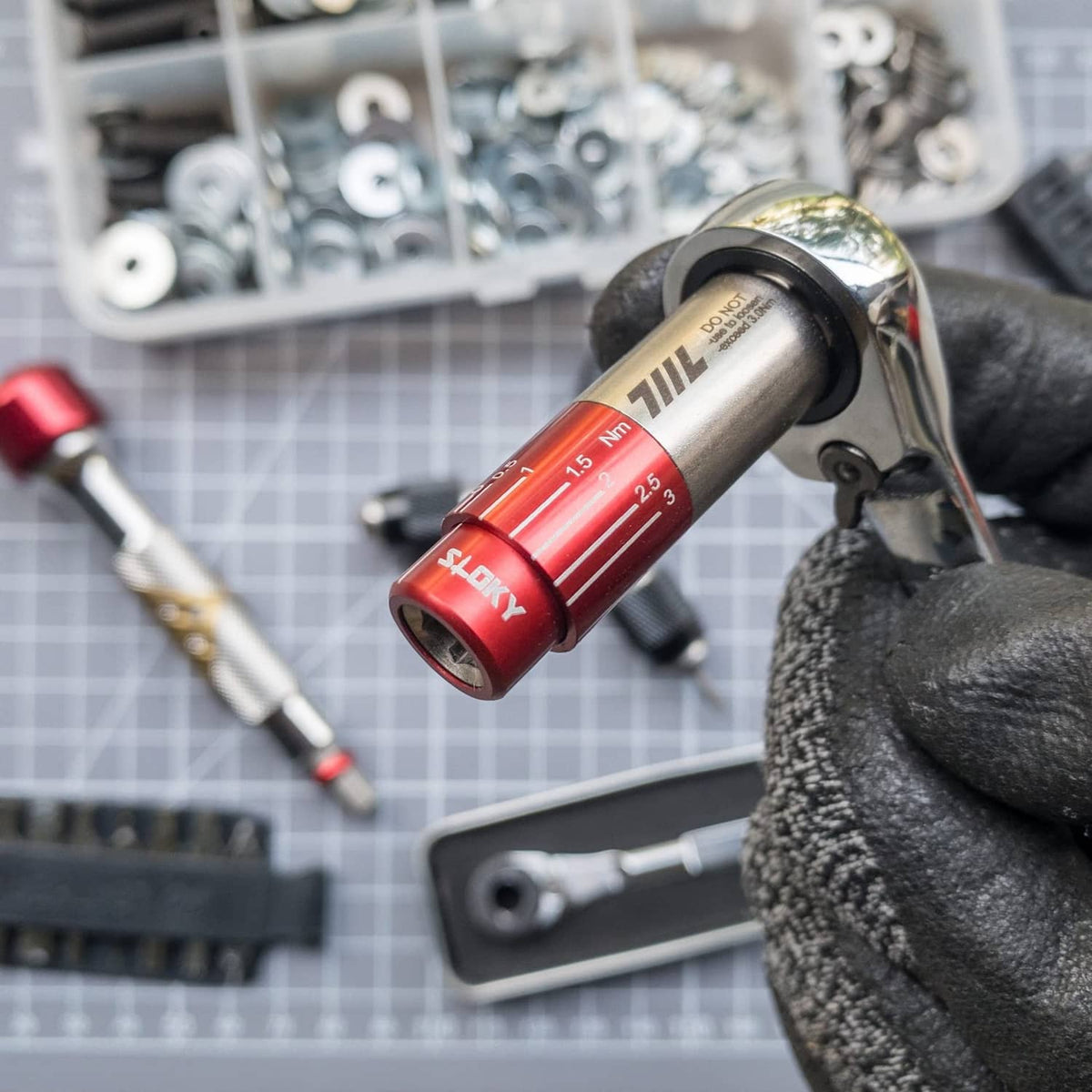 Red mini torque driver socket wrench, showing 0.5–2.5 Nm scale in gloved hand