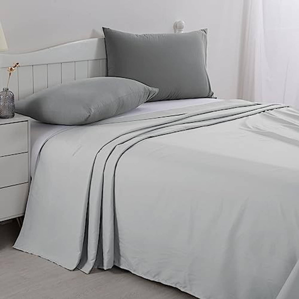 Light grey oversized king flat sheet neatly laid with pillows on bed