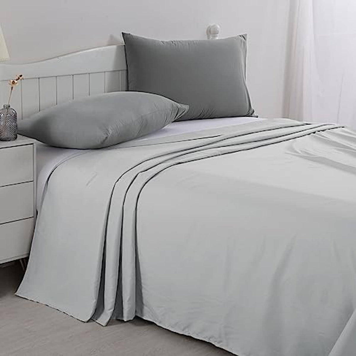 Light grey oversized king flat sheet neatly laid with pillows on bed