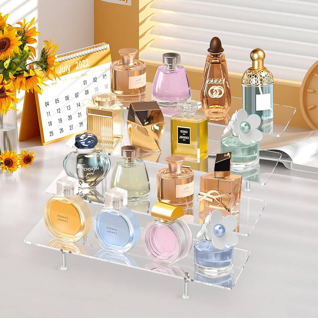 Clear 4-tier acrylic display stand holding perfume bottles and cosmetics