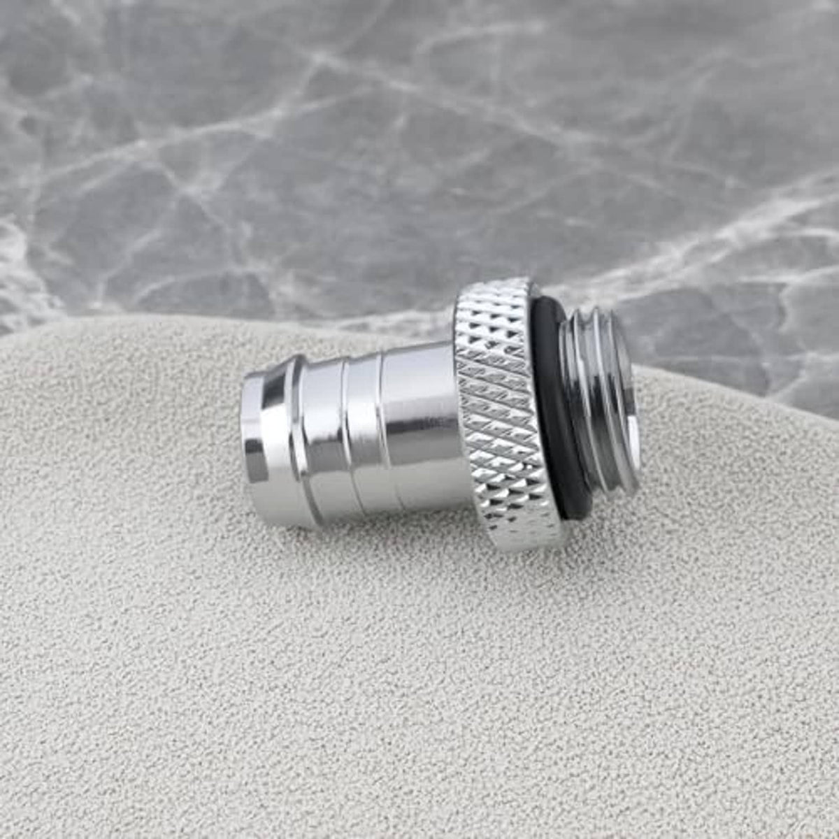 Silver hose barb fitting connector on speckled surface, knurled grip and black seal