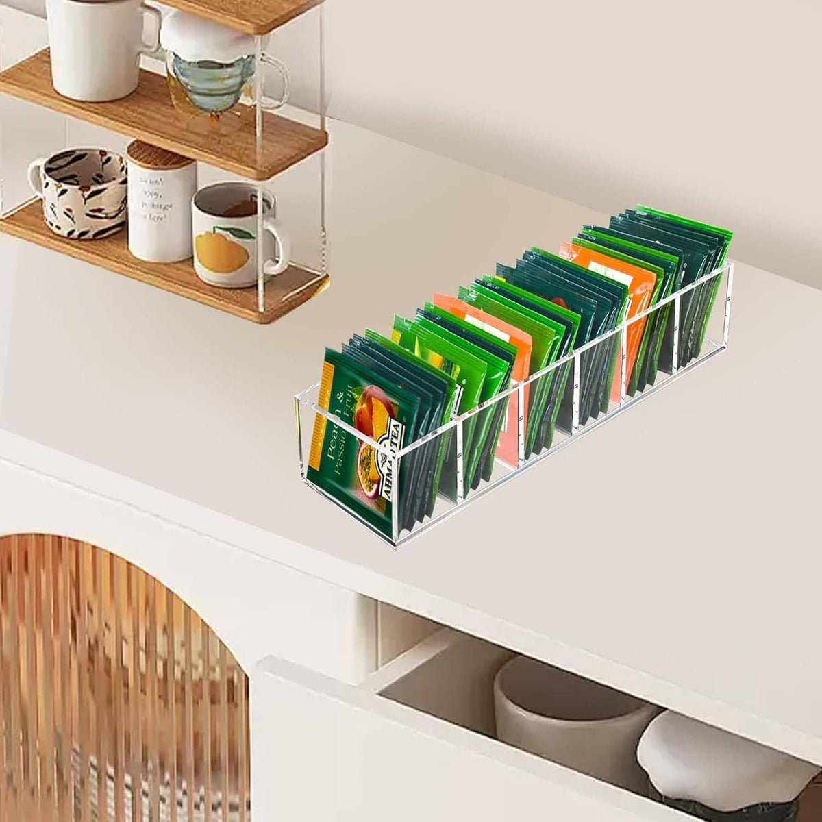 Clear acrylic tea bag organizer on shelf with tea packets arranged in front slots