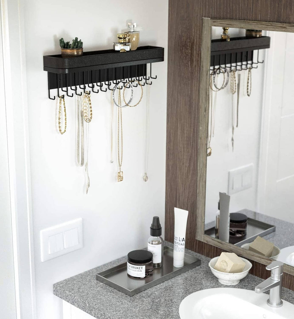 Black wall-mounted necklace holder with multiple hooks and wide top display bar