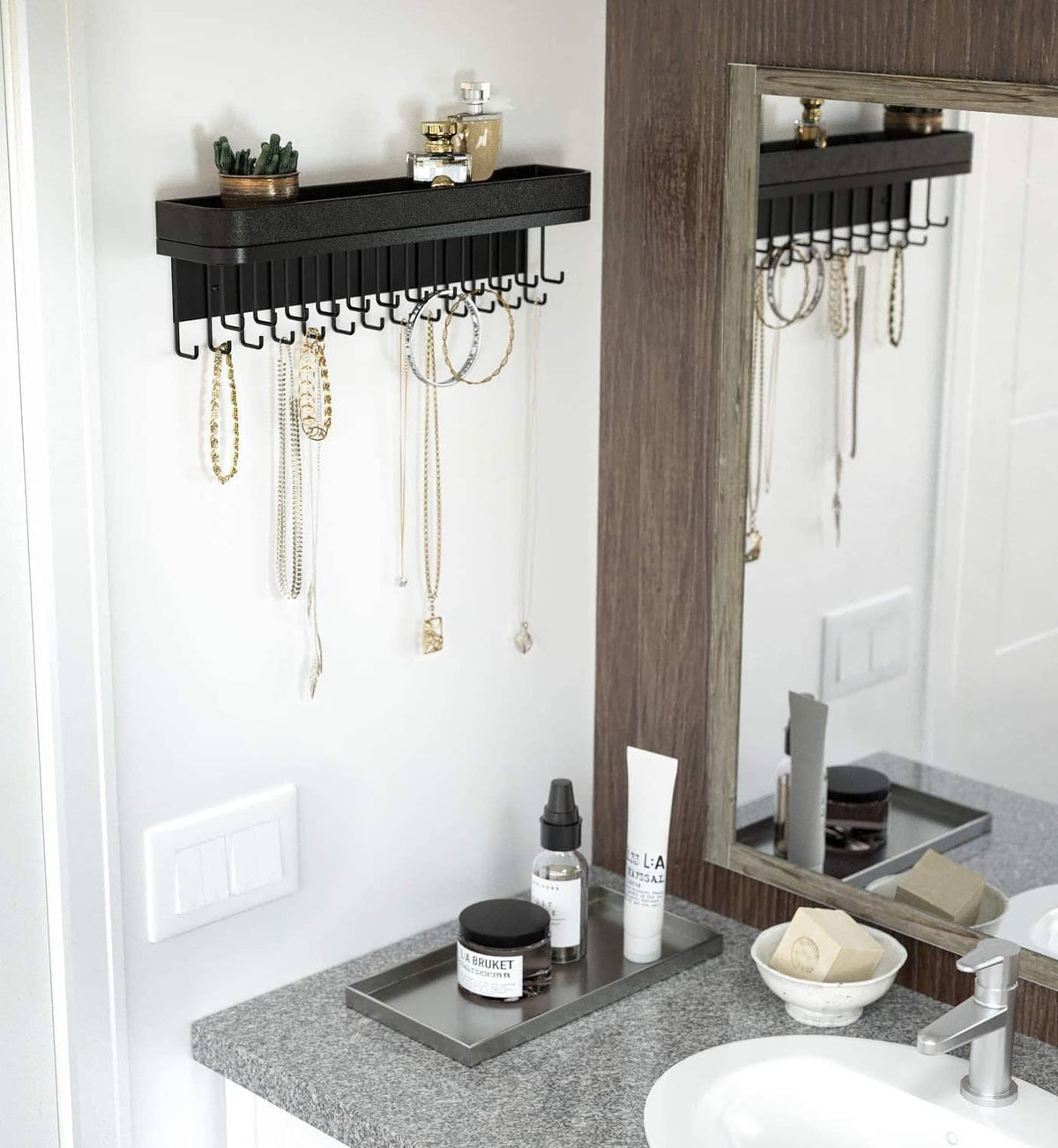 Black wall-mounted necklace holder with multiple hooks and wide top display bar