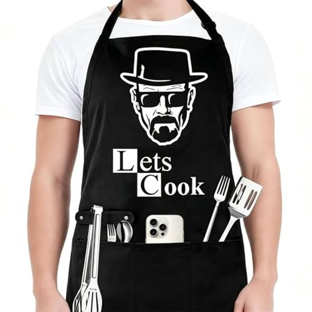 Black apron with 'Lets Cook' slogan and chef-face graphic; front pocket panel