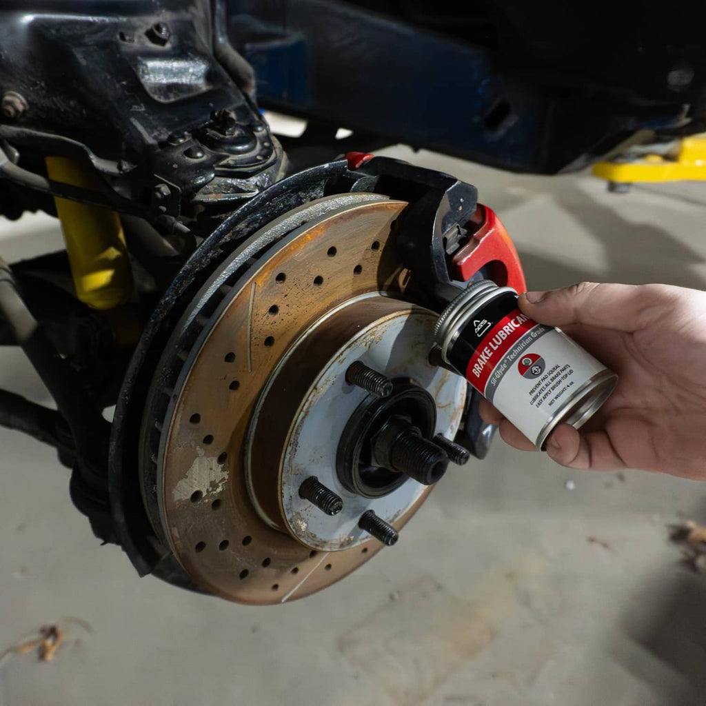 Technician brushes silicone brake lubricant onto brake rotor area