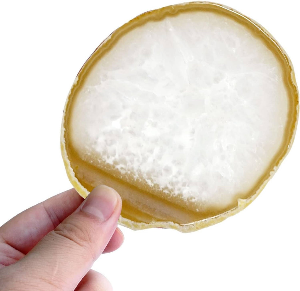 Round agate geode coaster in cream and gold, held by hand