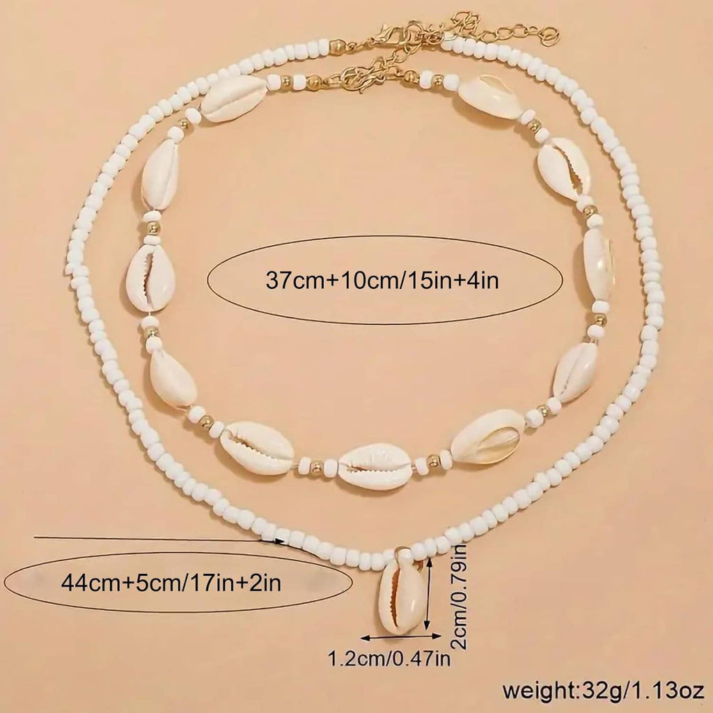 Adjustable cowrie shell necklace with white bead strands and gold-tone chain, flat lay