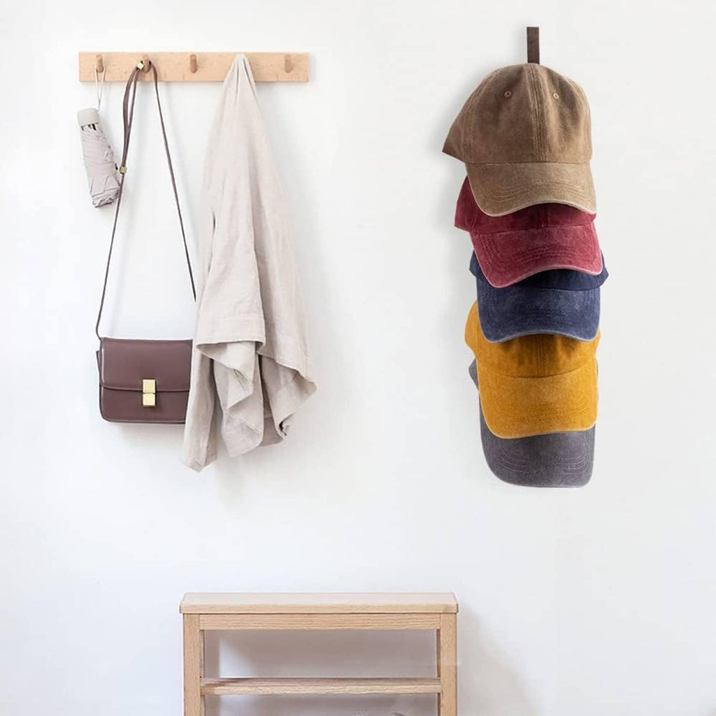 Wall-mounted wooden cap organizer holding multiple baseball caps on curved hooks