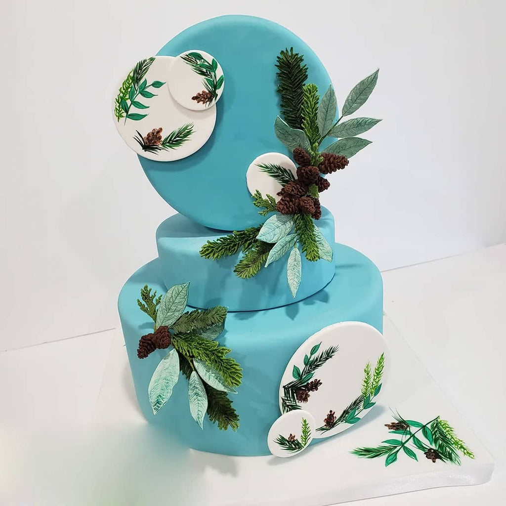 Blue wedding cake topper with green leaf and pinecone foliage decorations