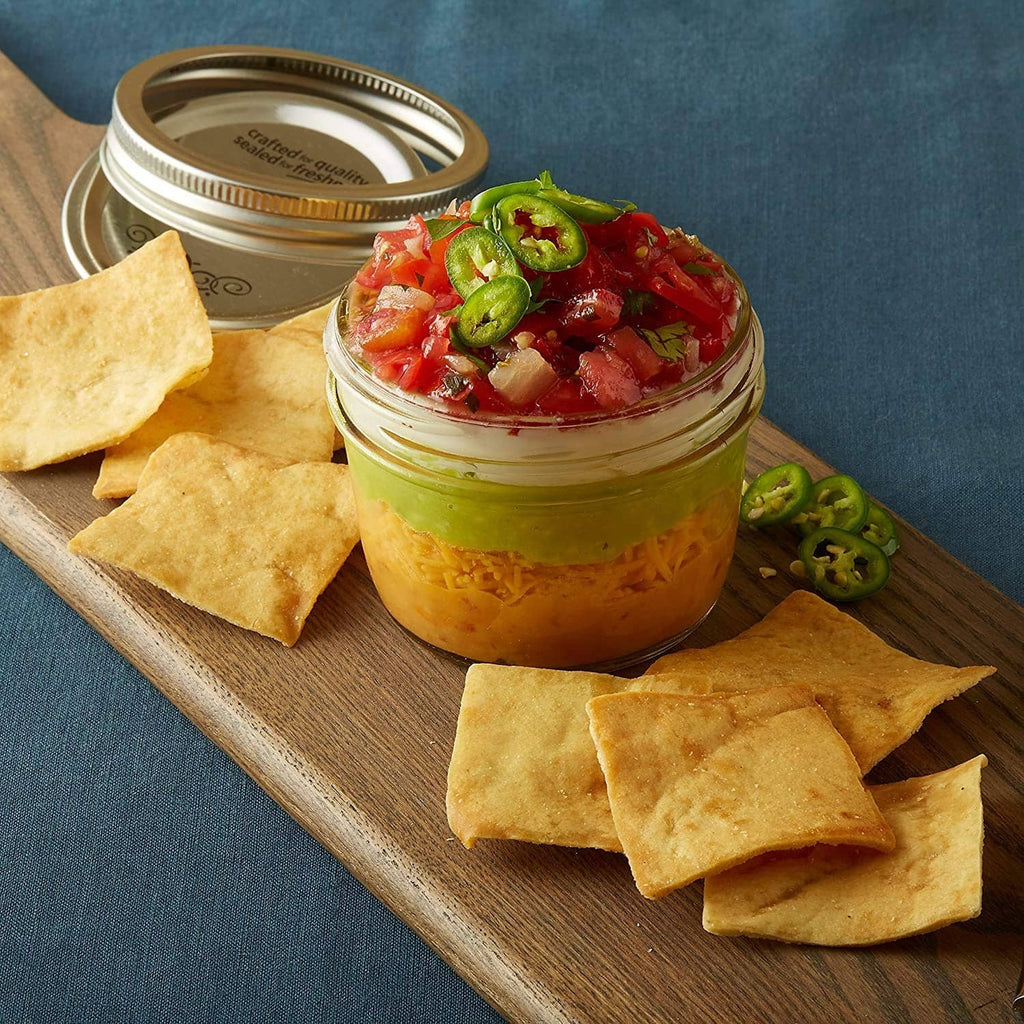 Pita chips with jarred tomato dip and green herb topping