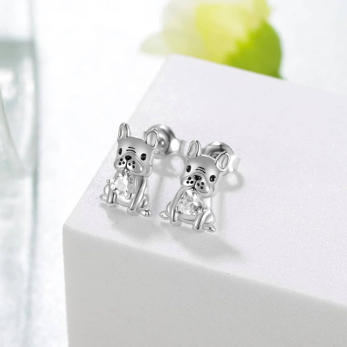 Silver French bulldog stud earrings with clear crystal, shown as a pair on a stand