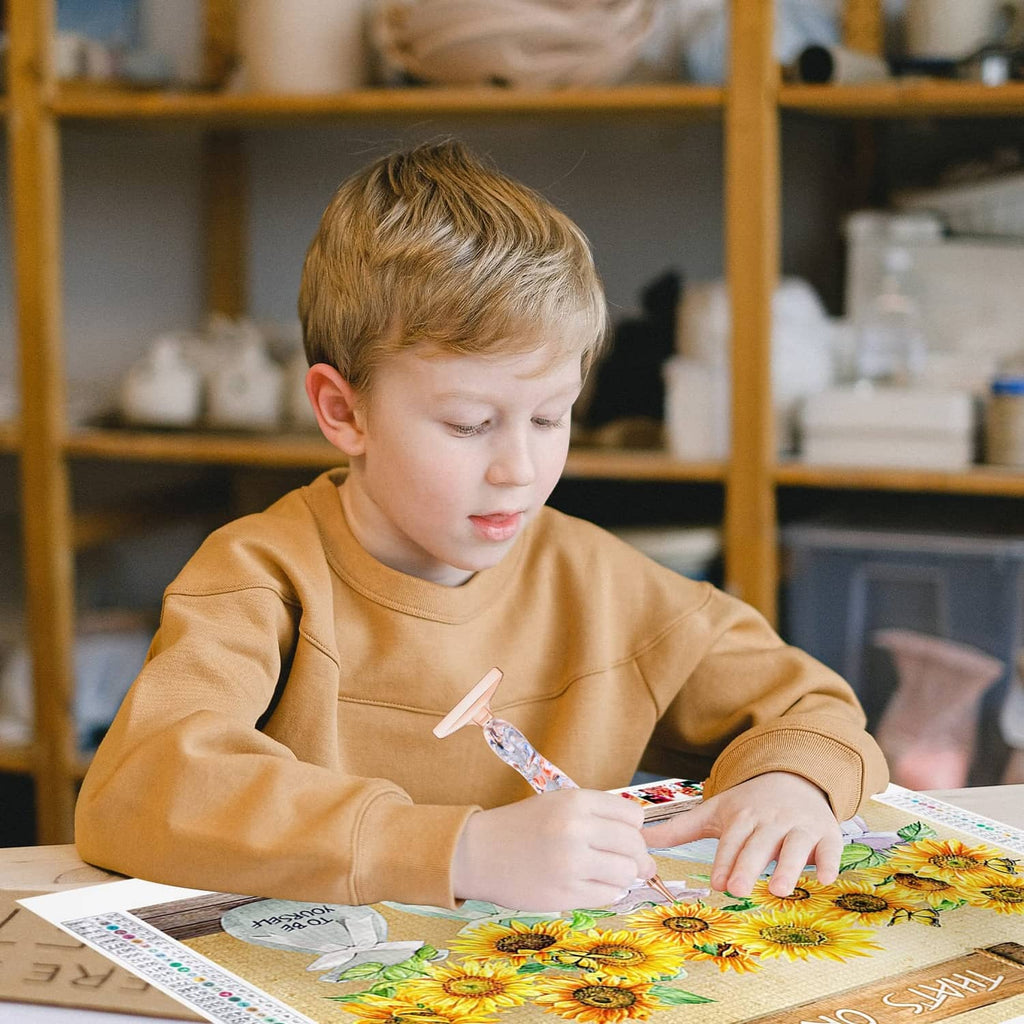 Child using a diamond painting pen on a sunflower craft canvas, swirled rose-gold tip