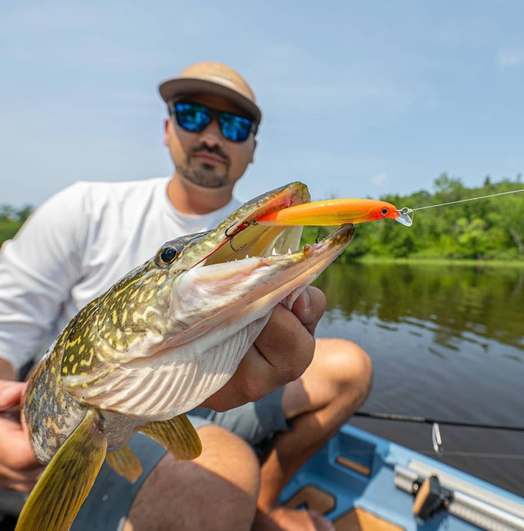 Orange and silver jerkbait with treble hooks, held with fish