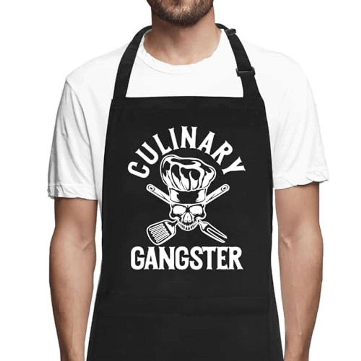 Black apron with skull-and-utensils print and adjustable neck strap on model.