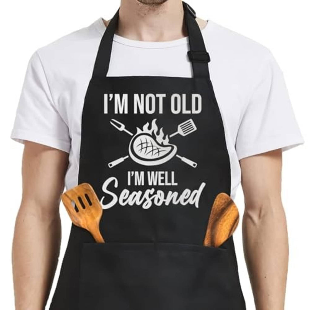 Black apron with 'I'm well seasoned' chef-graphic and wood spatula icons