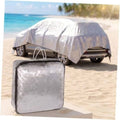 Reflective shade cloth cover in silver-gray with grommets, protecting an outdoor car