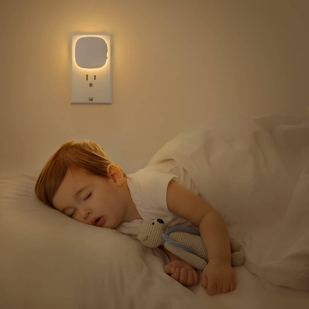 Warm white plug-in LED night light on wall above a sleeping child