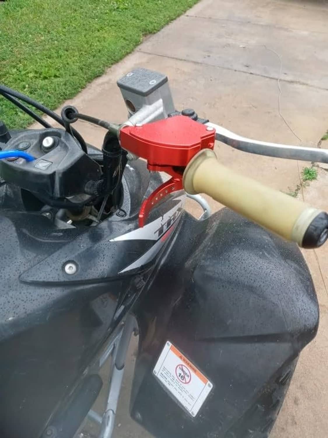 Red 7/8 in handlebar thumb throttle installed on a vehicle handlebar with black grip
