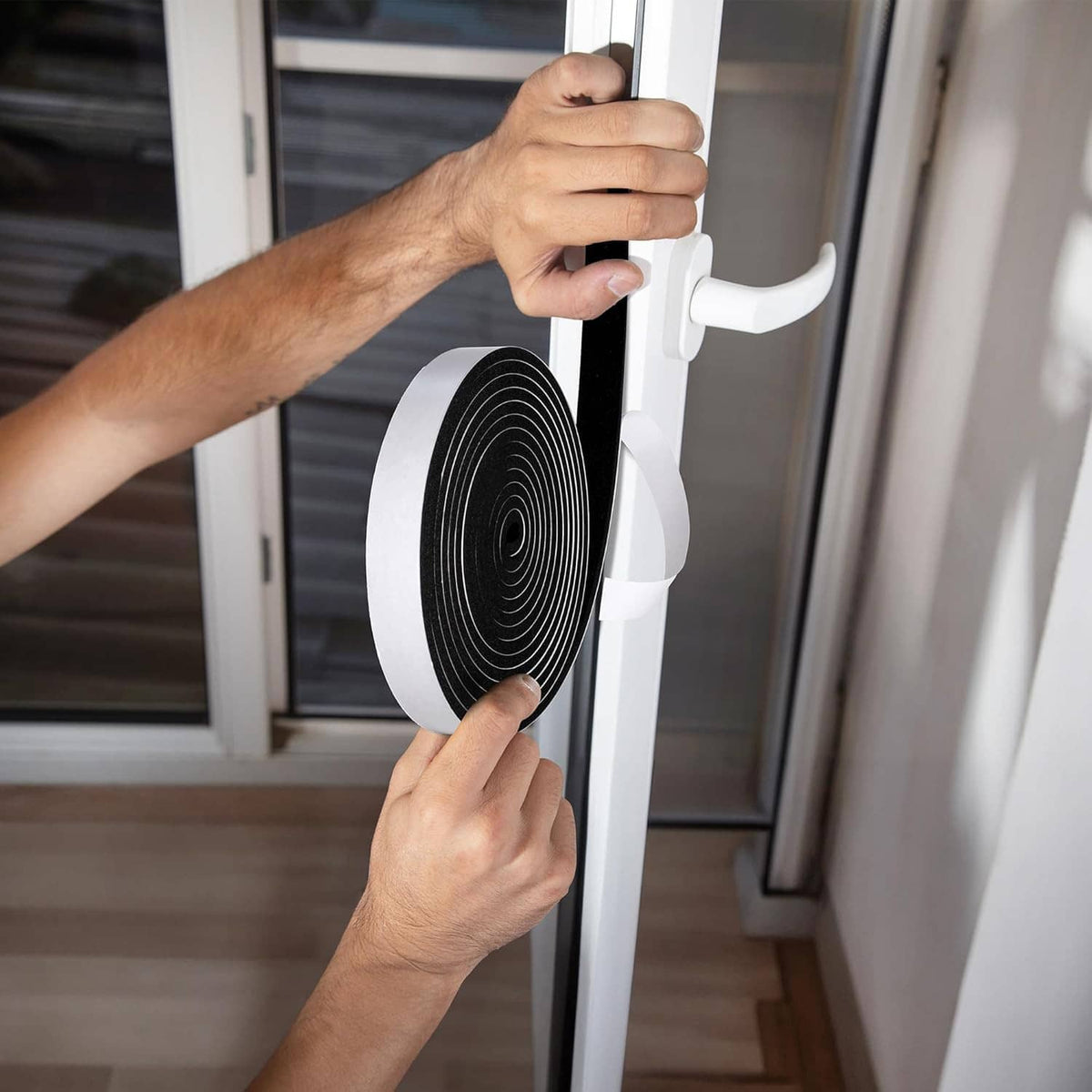 Foam weather stripping tape being applied to a door or window frame