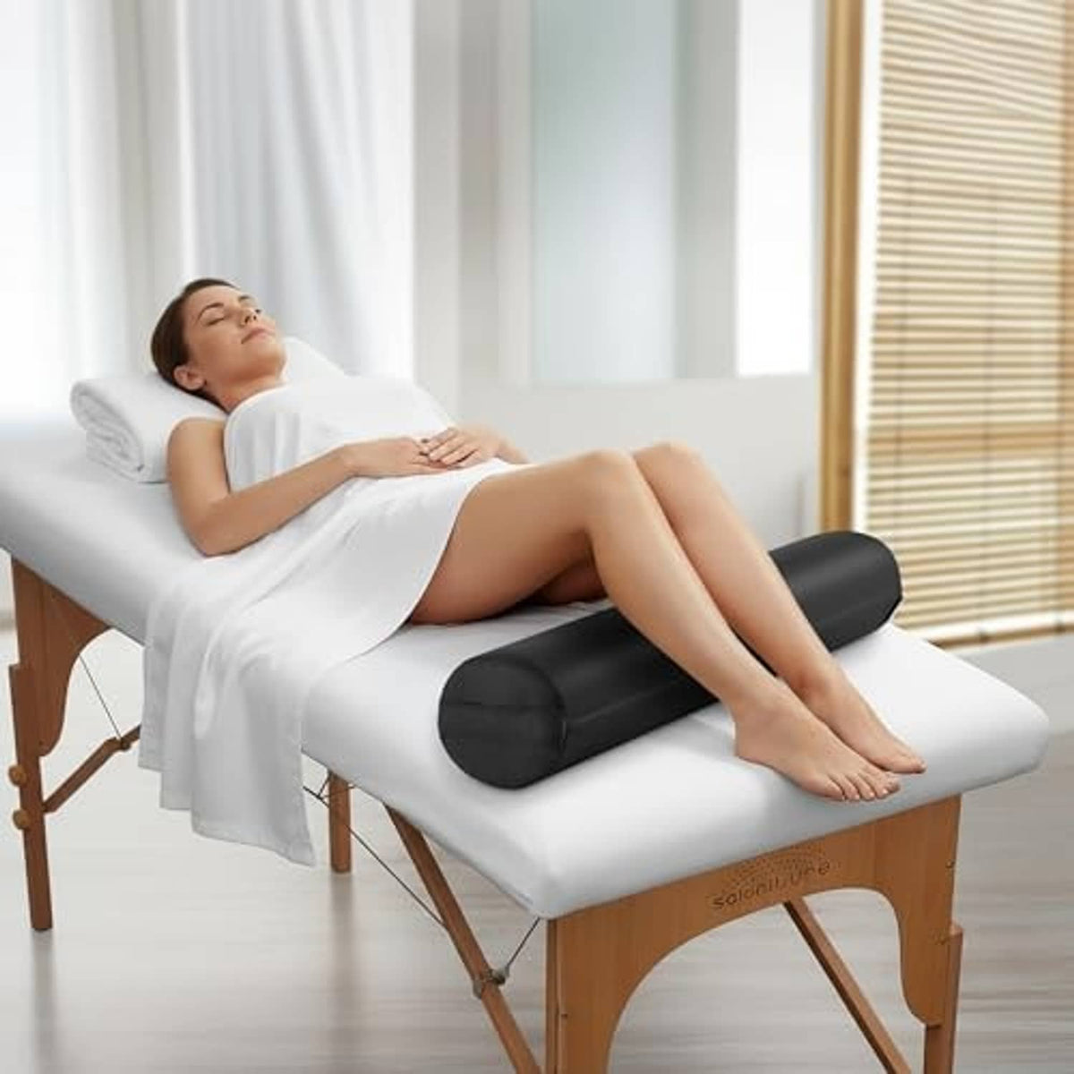 Black massage table bolster pillow pad placed under legs during treatment