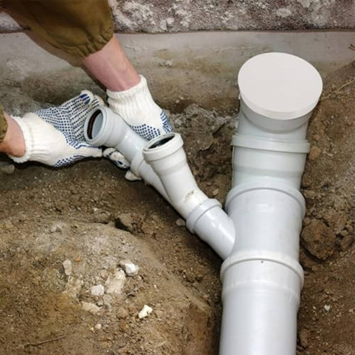 White PVC pipe end cap fitted on a drainage pipe, outdoor installation