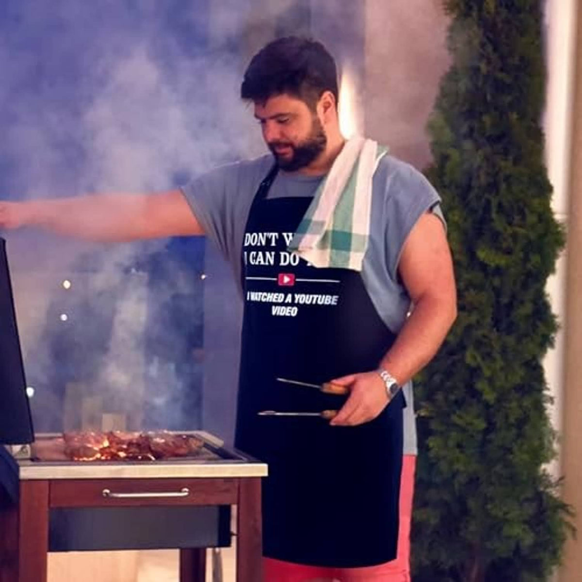 Black cooking apron with “Don't worry, I can do this” slogan while grilling