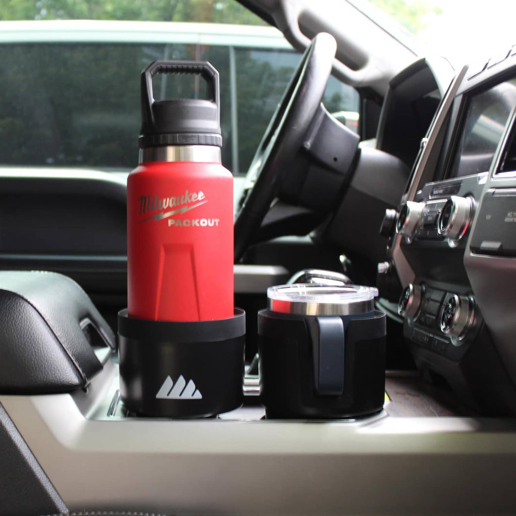 Black car cup holder expander holding a red bottle on the console