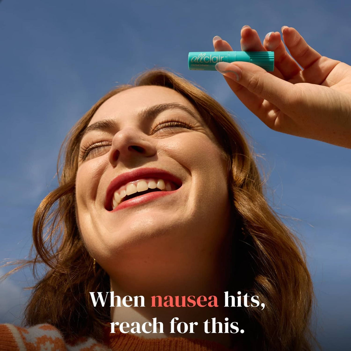 Turquoise herbal inhaler stick held up in a hand against the sky