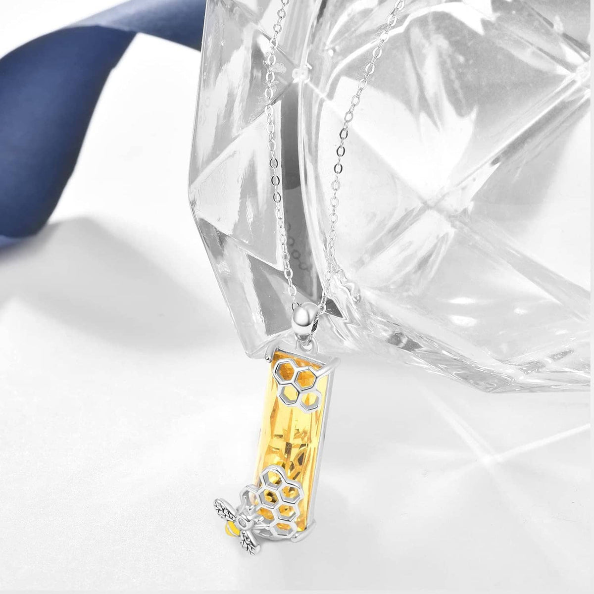 Close-up of silver necklace pendant with faceted yellow crystal and honeycomb pattern