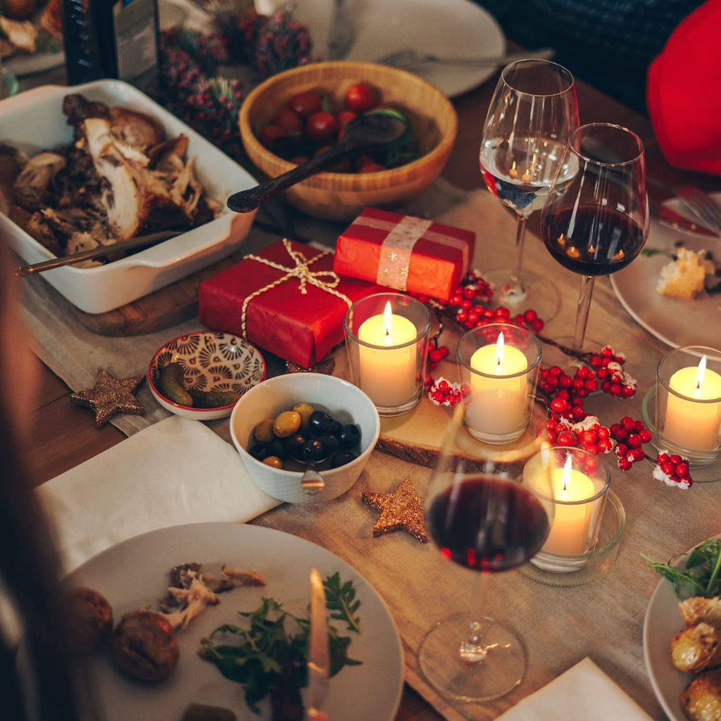 Clear glass candle holders with lit tea lights among holiday table items